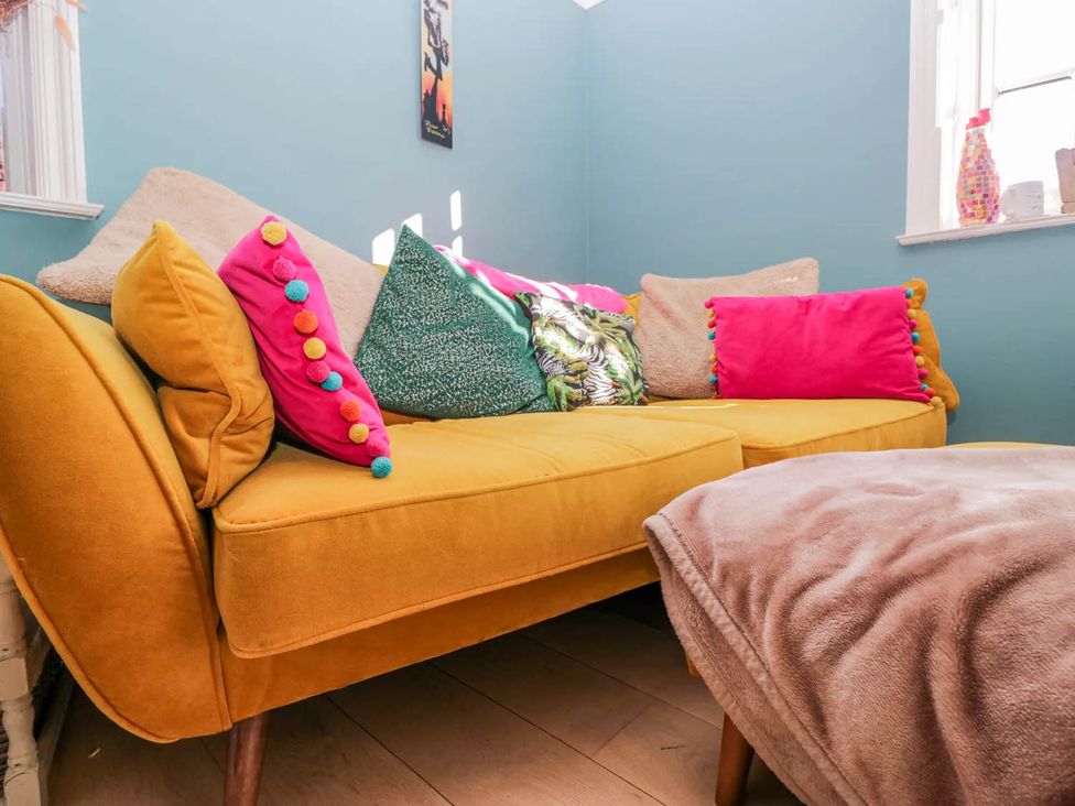 A living room with a yellow sofa and cushions at Somerby in St Bees