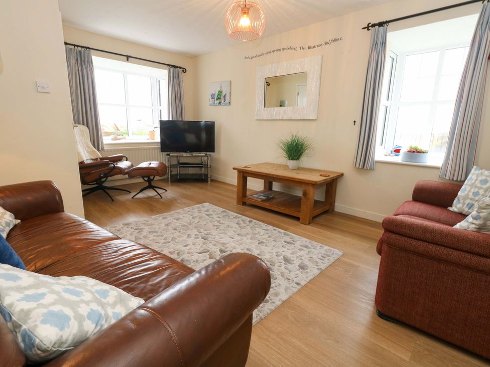 A living room with a coffee table and television at Still Waters in Weymouth
