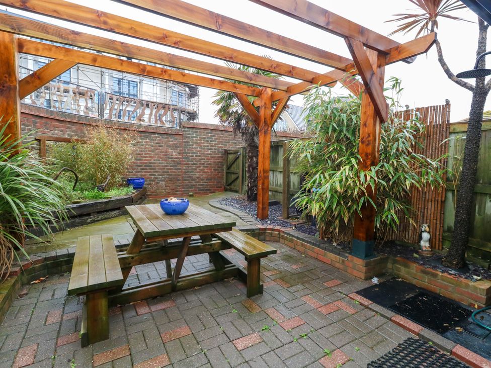 A garden with a wooden table and bench at Still Waters in Weymouth