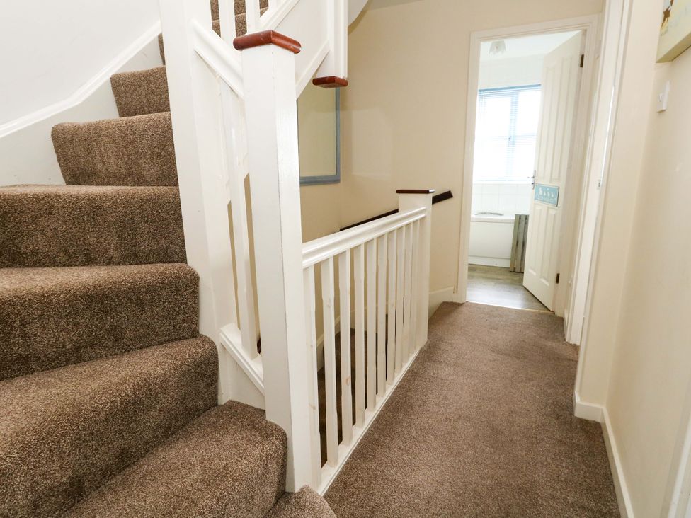 A hallway with stairs and a door leading to a bathroom at Still Waters in Weymouth