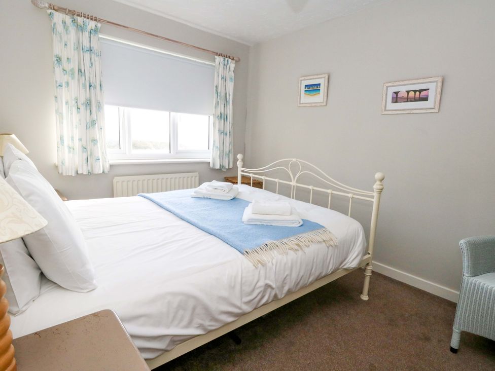 A bedroom with a bed, window, and chair at Still Waters in Weymouth