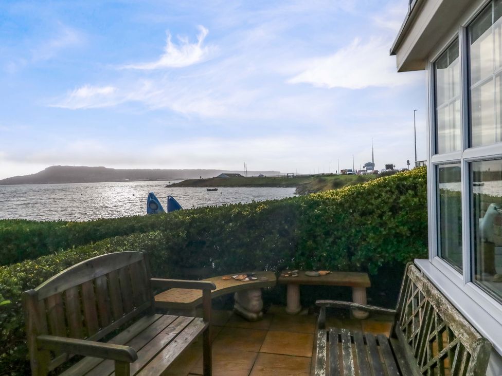 An outdoor area with benches and water view at Still Waters in Weymouth