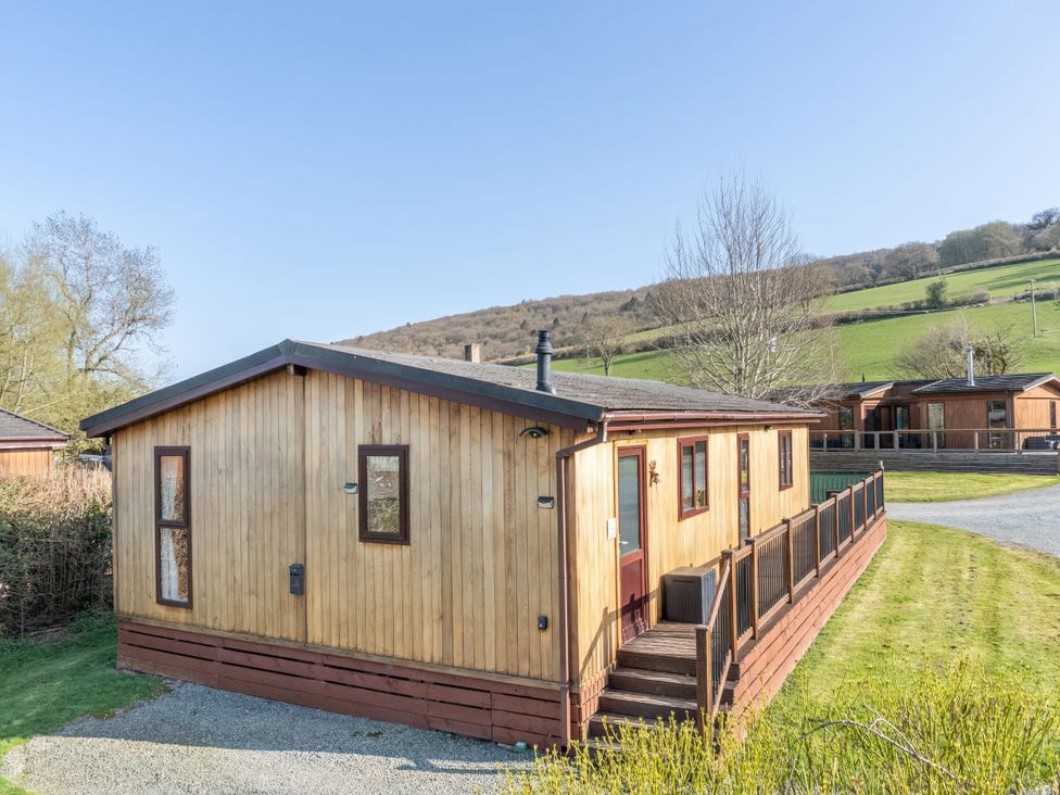 A log cabin with a deck and garden at Hazel Lodge in Craven Arms