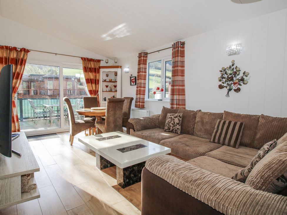A living room with a sofa and dining area at Hazel Lodge Clunton near Clun