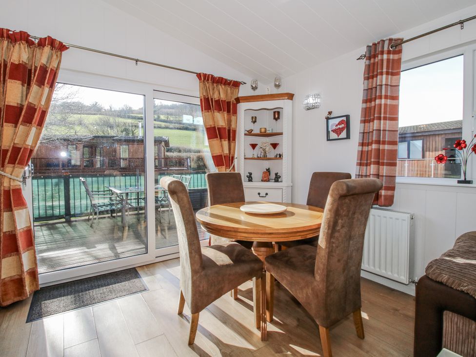 A dining room with a round table and chairs at Hazel Lodge in Clunton near Clun