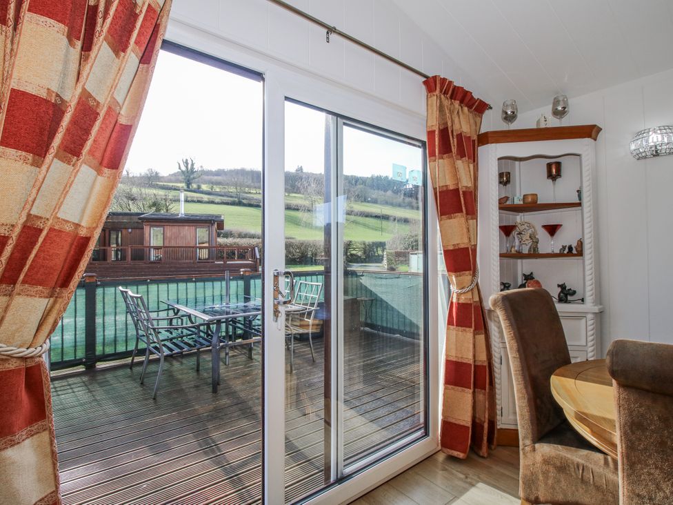 A dining room with a sliding door and table at Hazel Lodge in Clunton near Clun
