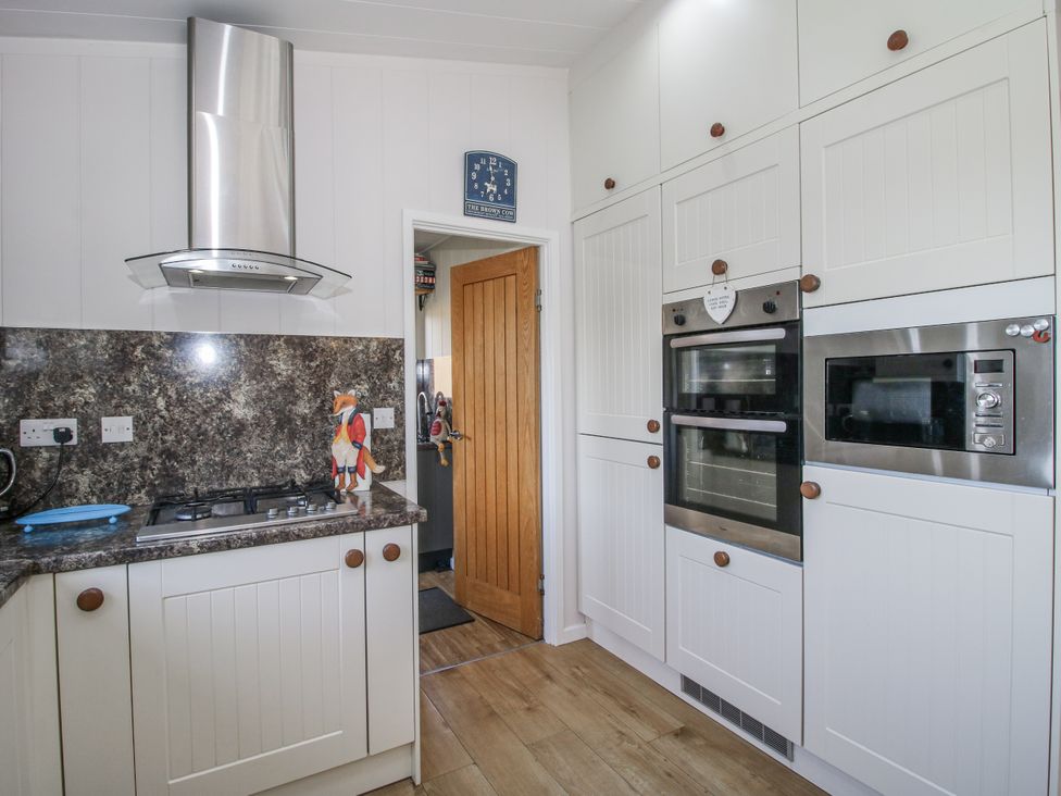 A kitchen with cabinets and appliances at Hazel Lodge in Clunton near Clun