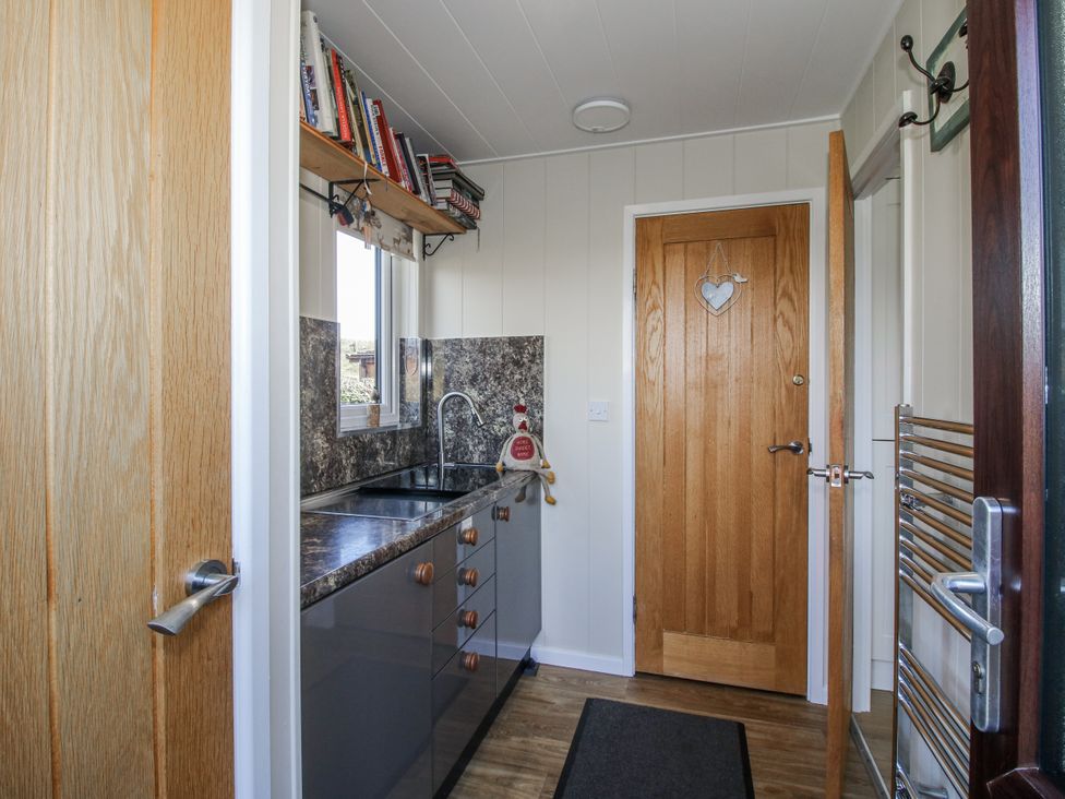 A kitchen with a sink and shelves at Hazel Lodge in Clunton near Clun