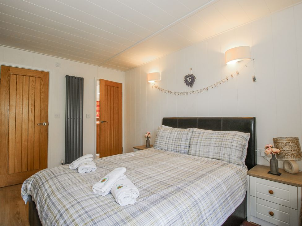 A bedroom with a bed and bedside table at Hazel Lodge in Clunton near Clun