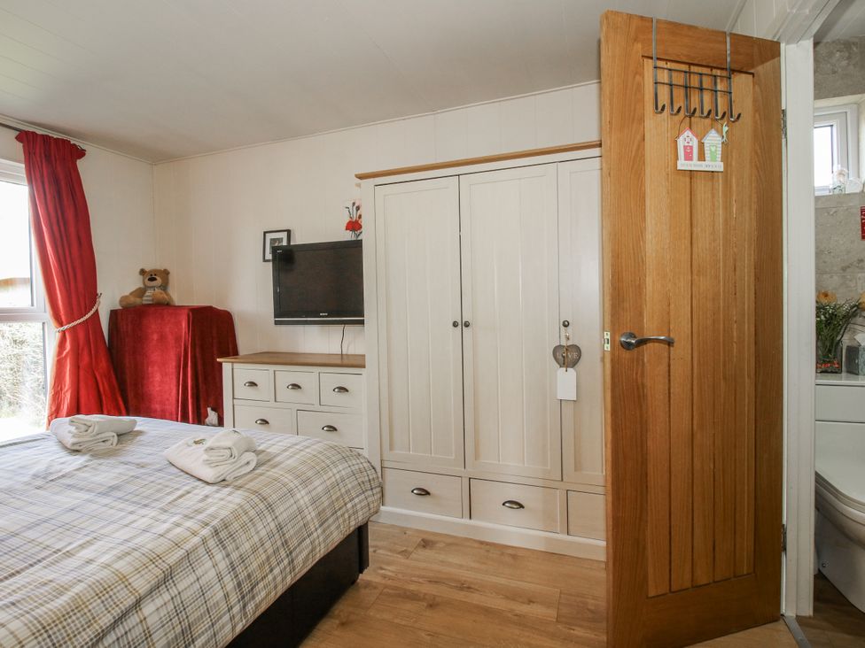 A bedroom with a bed and wardrobe at Hazel Lodge in Clunton near Clun