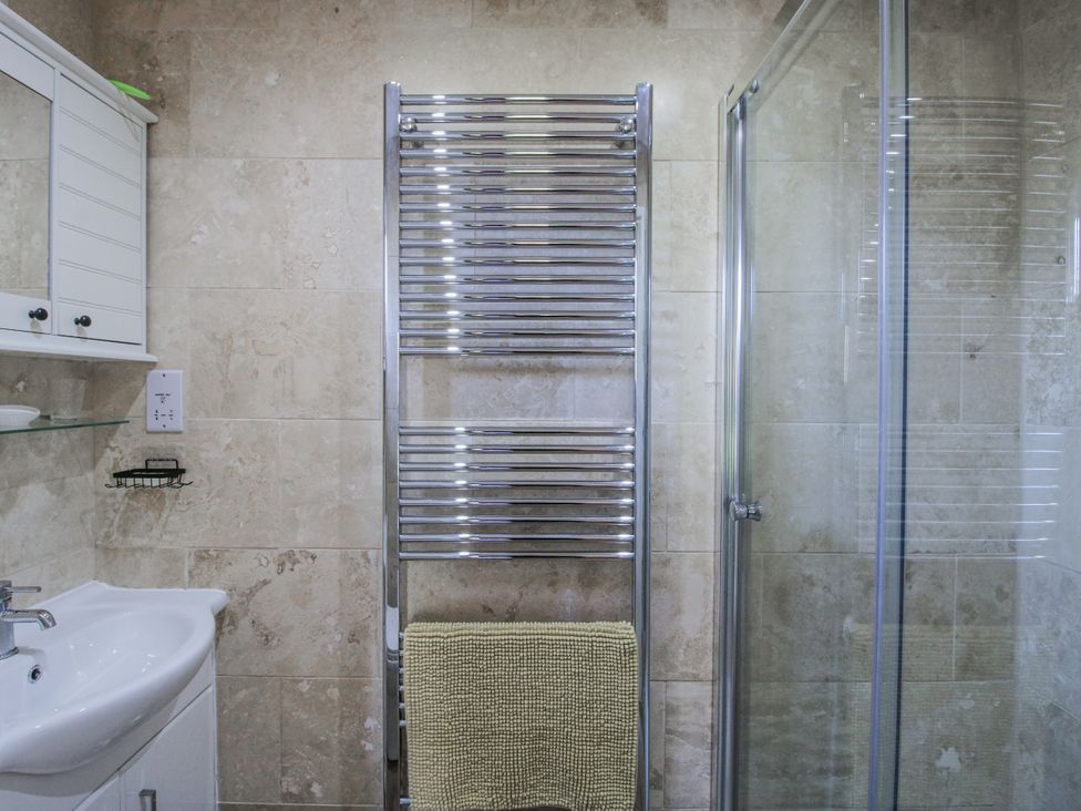 A bathroom with a sink, mirror, towel rail and shower at Hazel Lodge in Clunton near Clun