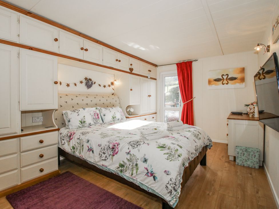 A bedroom with a bed and wardrobe at Hazel Lodge in Clunton near Clun