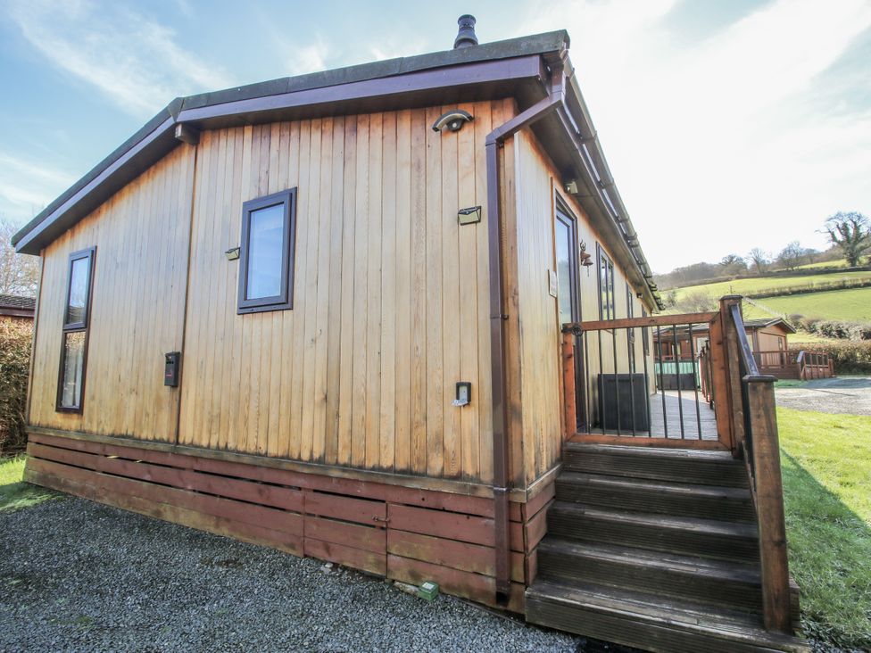 A wooden lodge exterior with stairs and deck at Hazel Lodge Clunton near Clun