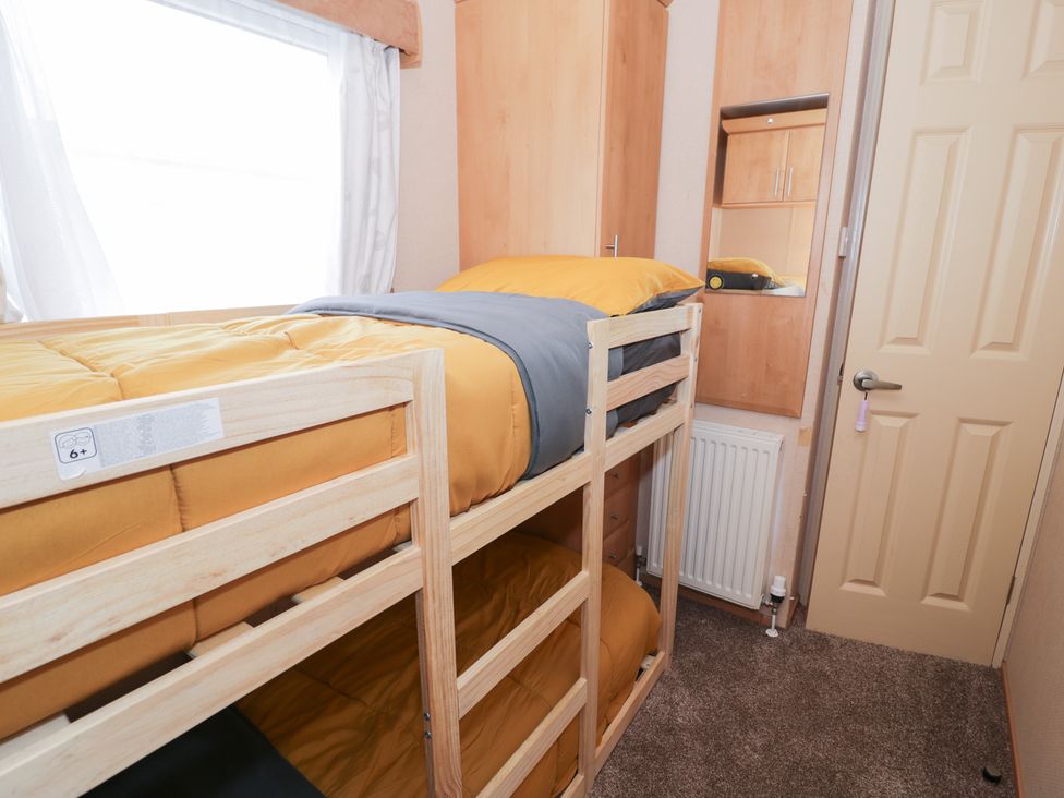 A bedroom with a bunk bed and wooden furniture at 11, Beachfields