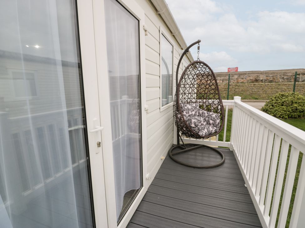 A balcony with a hanging chair at 11, Beachfields