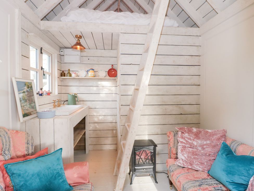 A living room with a ladder and a sofa at Shades Farm Cabin in Cirencester