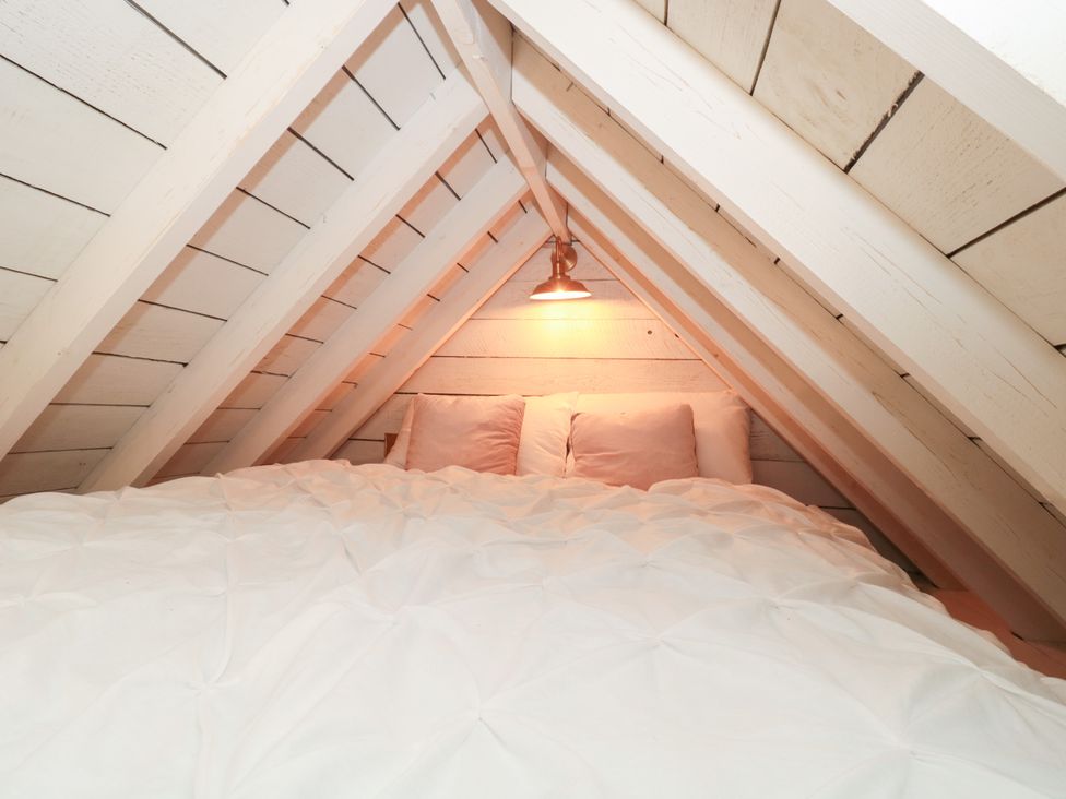 A bedroom with a bed and light fixture at Shades Farm Cabin in Cirencester