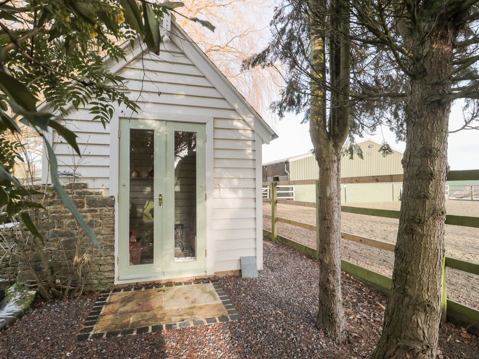 A shed with green doors and gravel pathway at Shades Farm Cabin Circenester