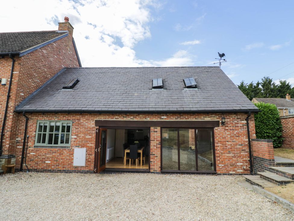 An outdoor view of a brick house with a gravel area at Underhill House Annex