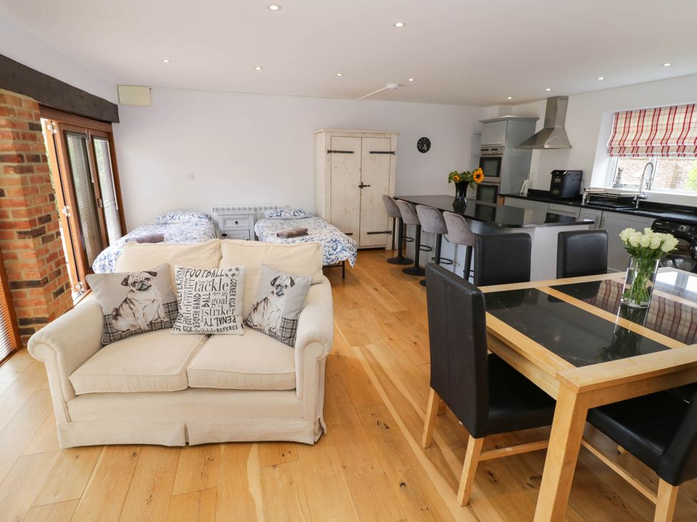 A living room with a sofa and kitchen area at Underhill House Annex