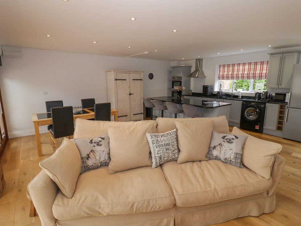 A living room with a sofa and kitchen area at Underhill House Annex Stratford-Upon-Avon