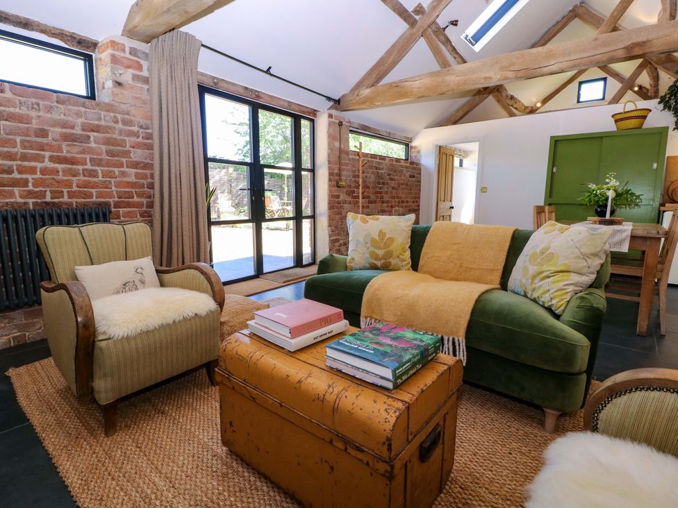 A living room featuring an armchair and a green sofa with a coffee table at The Barn 