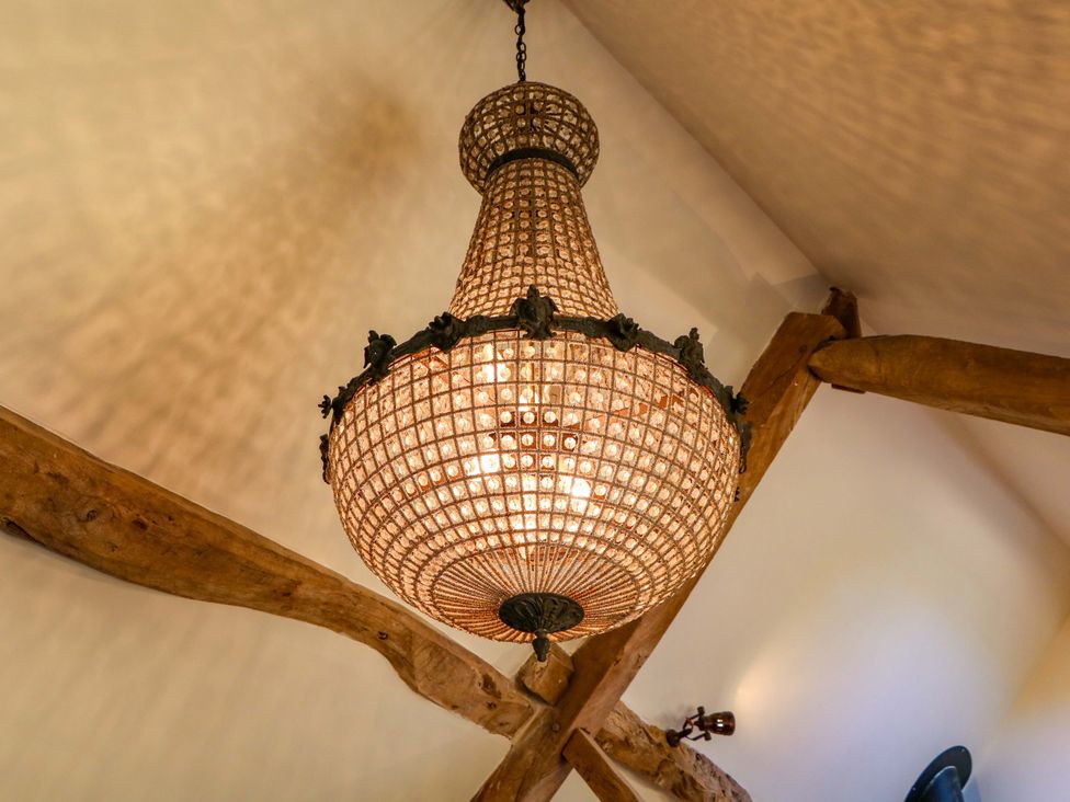 A chandelier hanging from wooden beams at The Barn in 