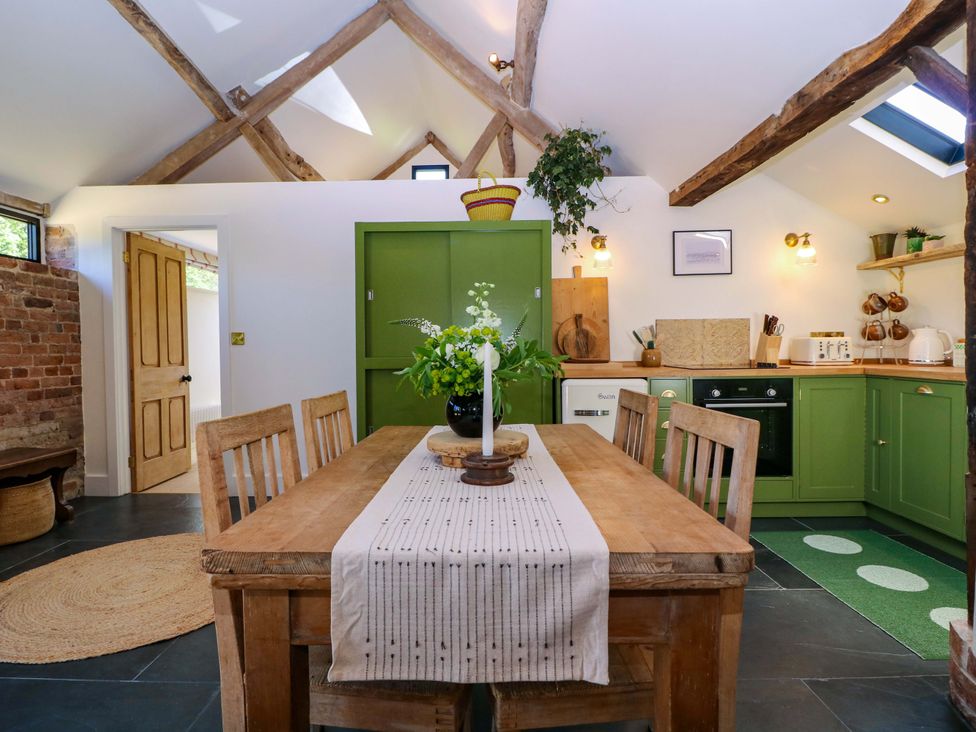 A kitchen with a dining table and green cabinets at The Barn in 