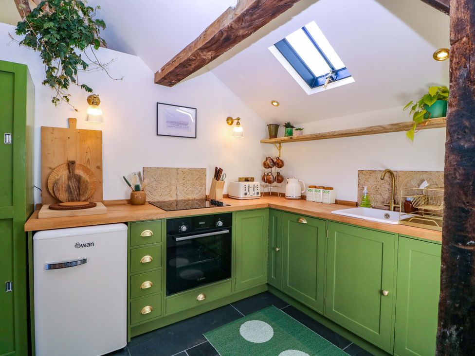 A kitchen with green cabinets and wooden shelves at The Barn