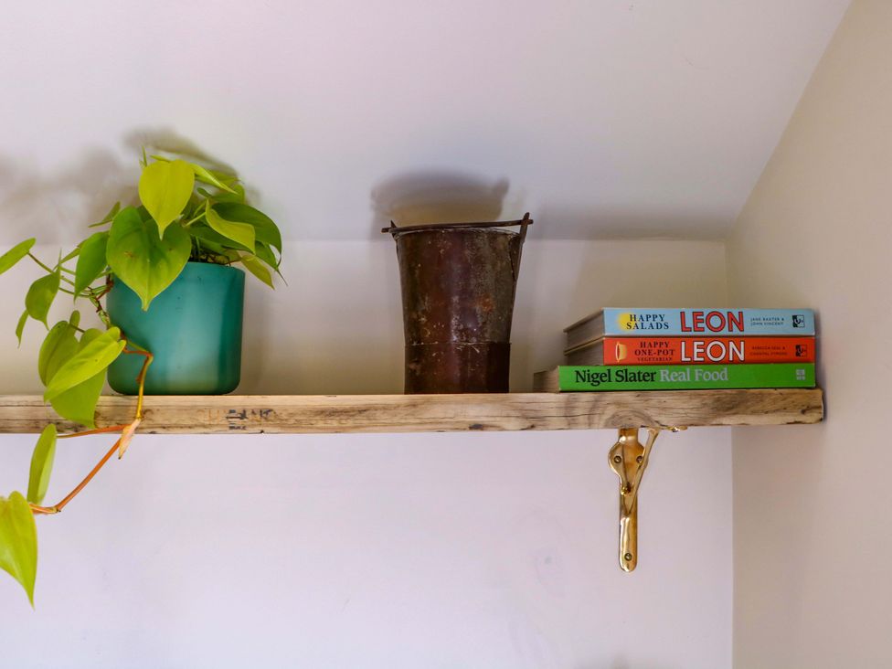 A shelf with a plant pot, a bucket, and cookbooks at The Barn 