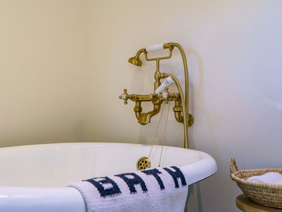 A bathtub with a gold faucet and a towel at The Barn in 
