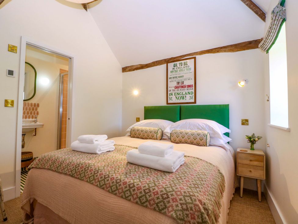A bedroom with a double bed and ensuite at The Barn 