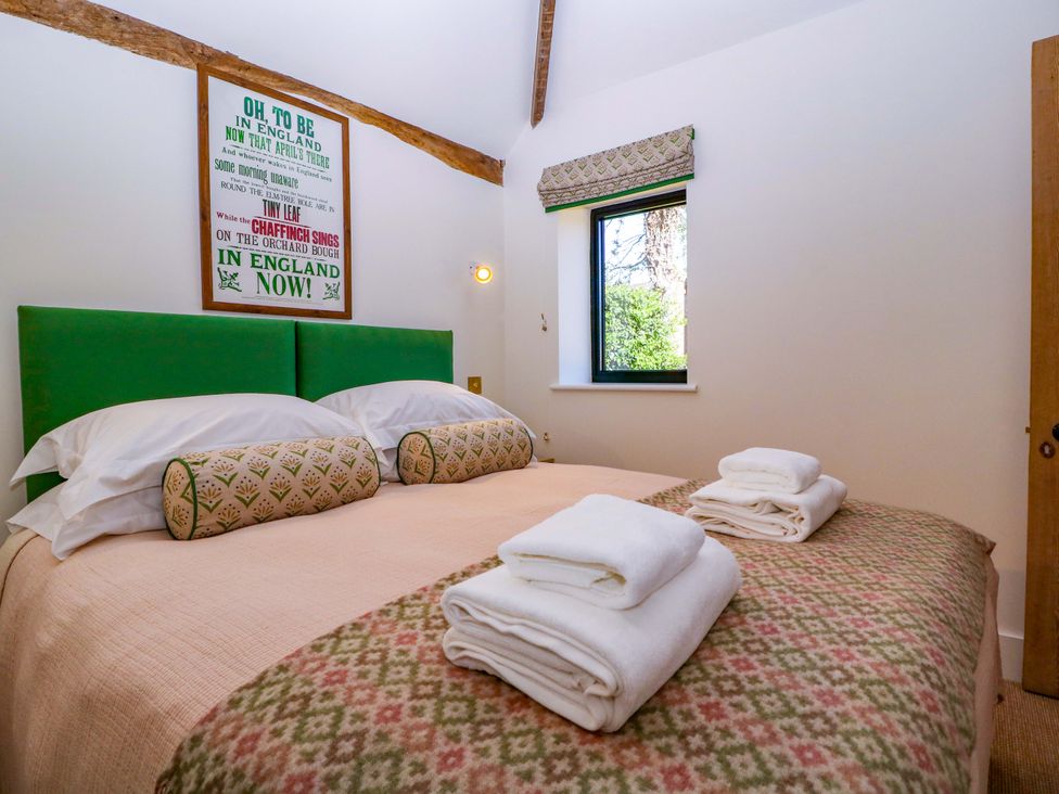 A bedroom with a green bed and white towels at The Barn
