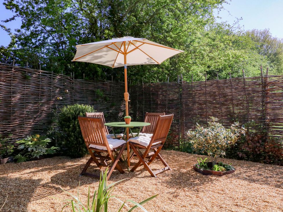A garden seating area with a table and chairs under an umbrella at The Barn in 