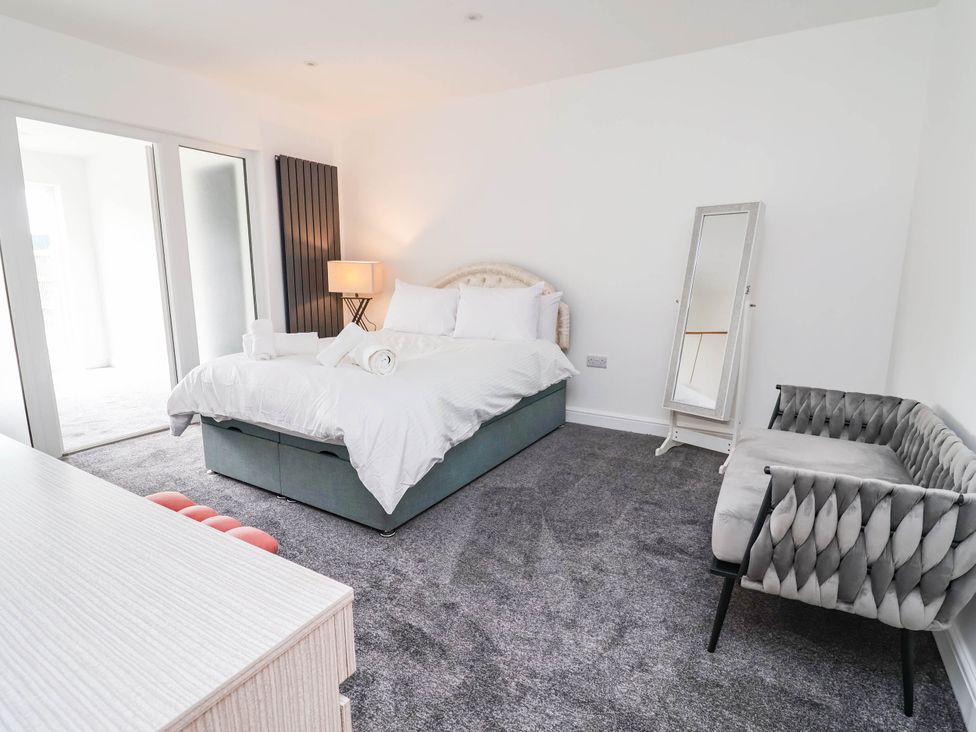A bedroom with a bed and mirror at 6 Bastion Close in Prestatyn