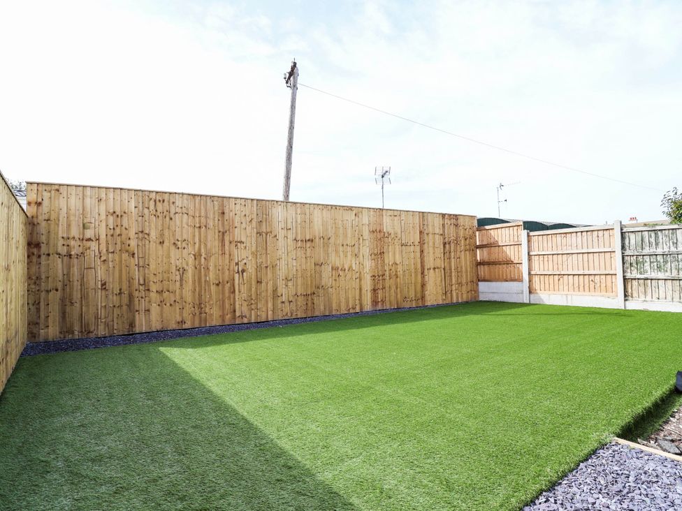 A garden with artificial grass and wooden fencing at 6 Bastion Close in Prestatyn