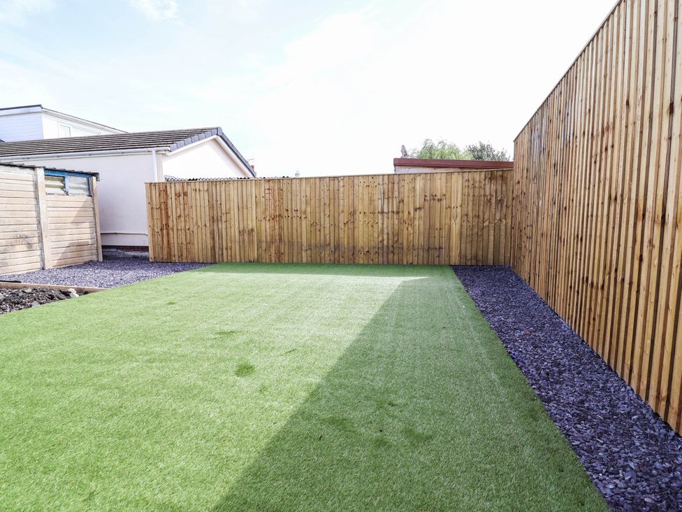 A garden with artificial grass and wooden fence at 6 Bastion Close in Prestatyn
