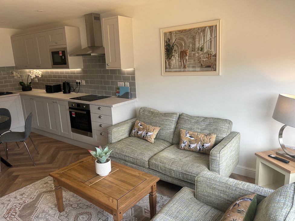 A living room with kitchen units and a sofa at 6 Bastion Close in Prestatyn
