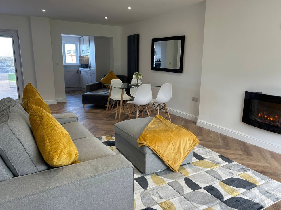 A living room with a sofa and dining area at 21 Bastion Gardens Prestatyn