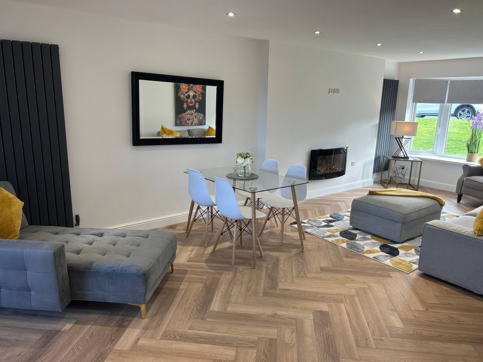 A living room with a sofa and dining table at 21 Bastion Gardens Prestatyn