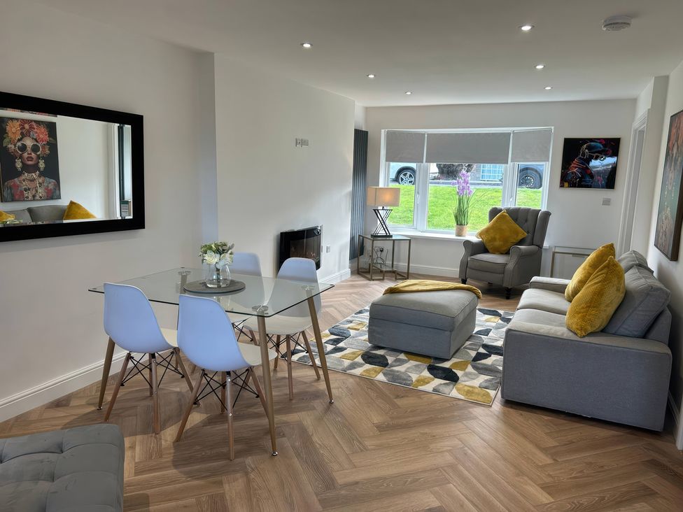 A living room with a glass table and seating area at 21 Bastion Gardens Prestatyn