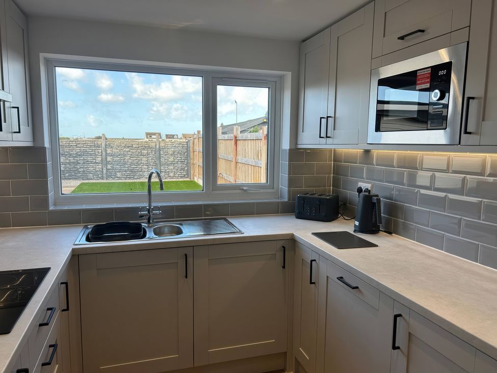 A kitchen with cabinets and a window at 21 Bastion Gardens Prestatyn