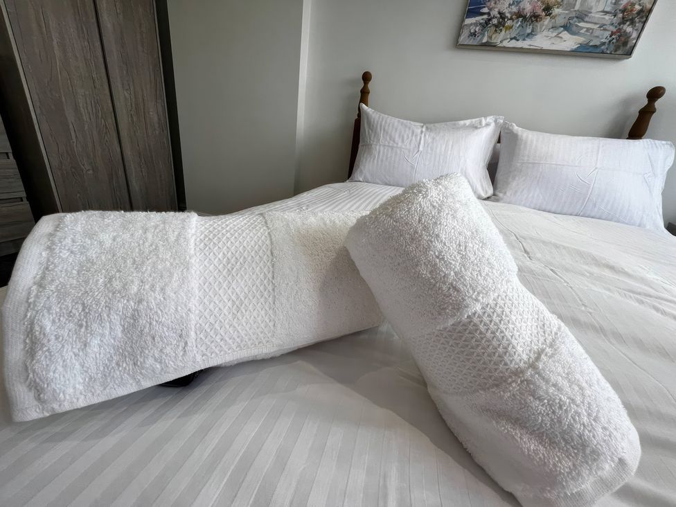 A bed with white towels and pillows at 21 Bastion Gardens in Prestatyn