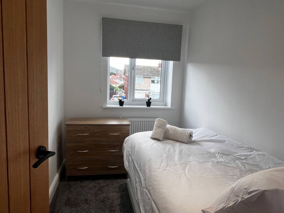 A bedroom with a bed, nightstand, and window at 21 Bastion Gardens in Prestatyn
