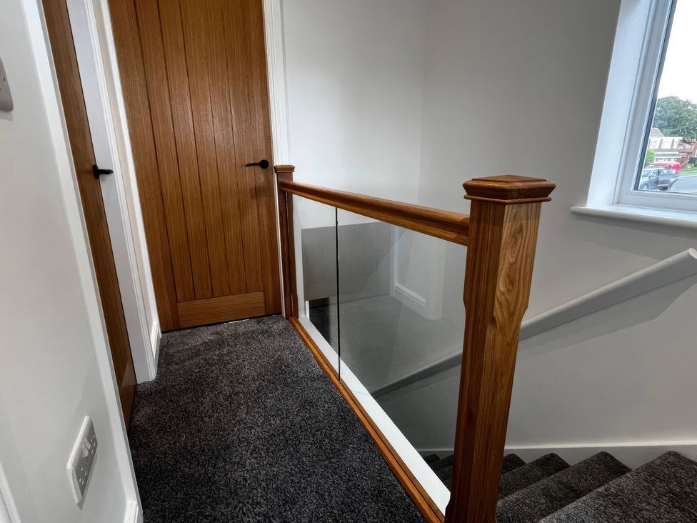 A staircase with a wooden railing and door at 21 Bastion Gardens Prestatyn