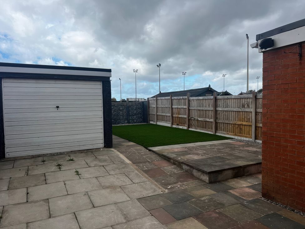 A garden with a garage and paved area at 21 Bastion Gardens Prestatyn