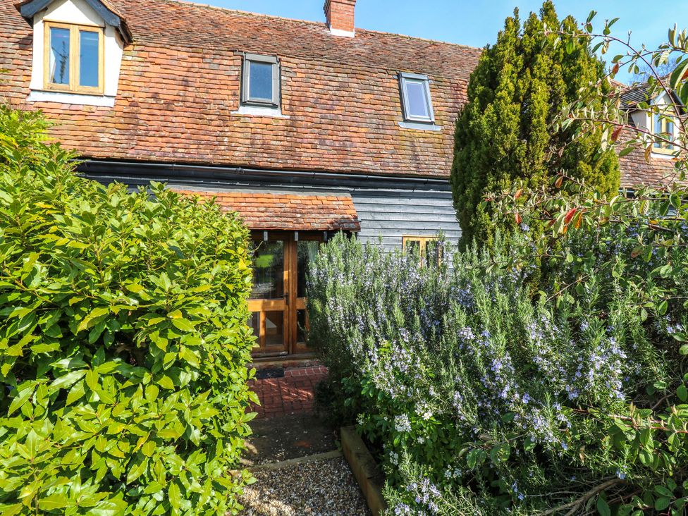 A house with a wooden door and windows surrounded by greenery at Six Apples in Wethersfield near Finchingfield