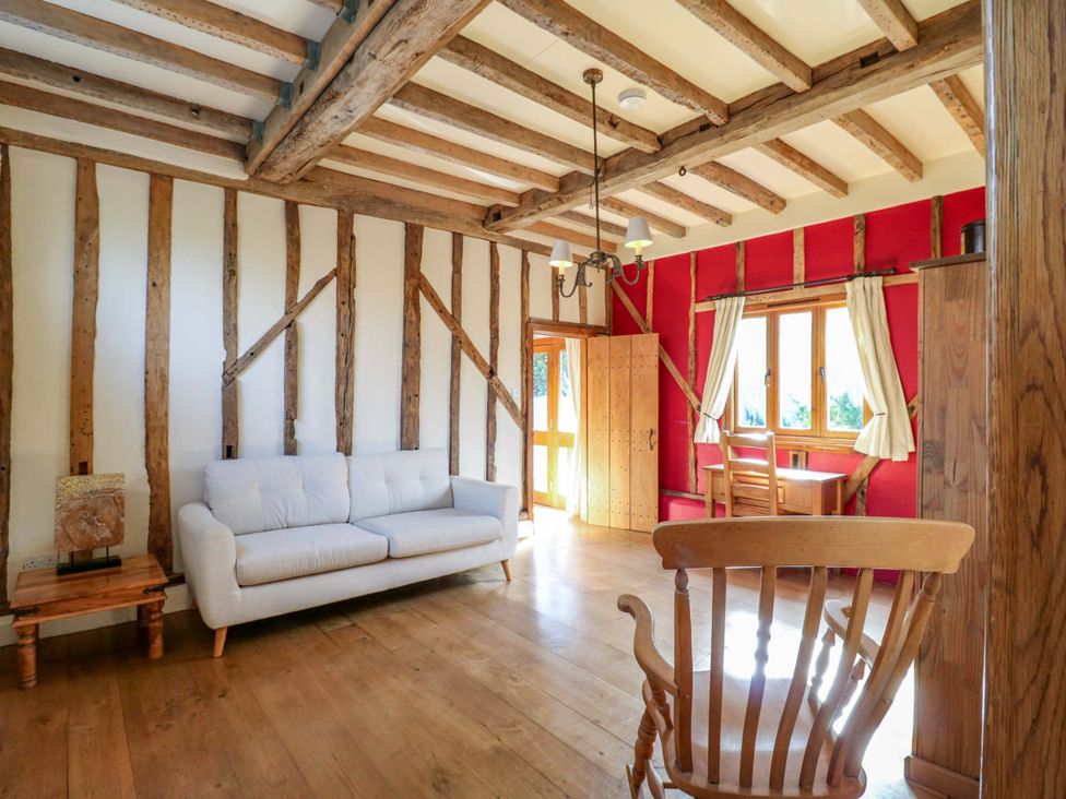 A living room with a sofa and wooden furniture at Six Apples in Wethersfield near Finchingfield