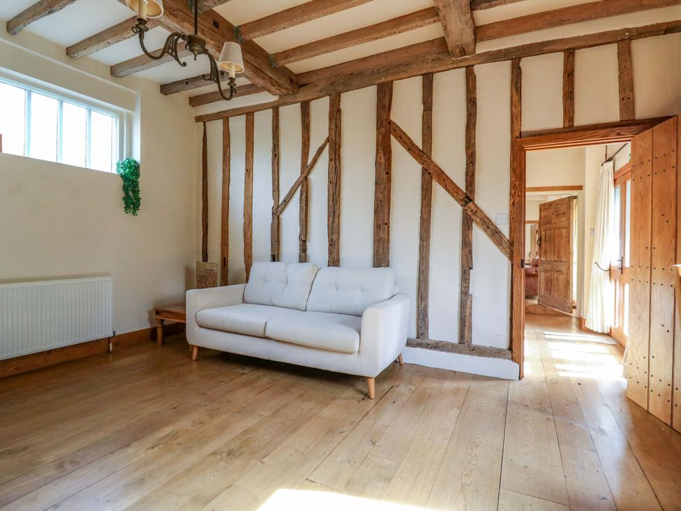 A living room with a sofa and wooden features at Six Apples in Wethersfield near Finchingfield