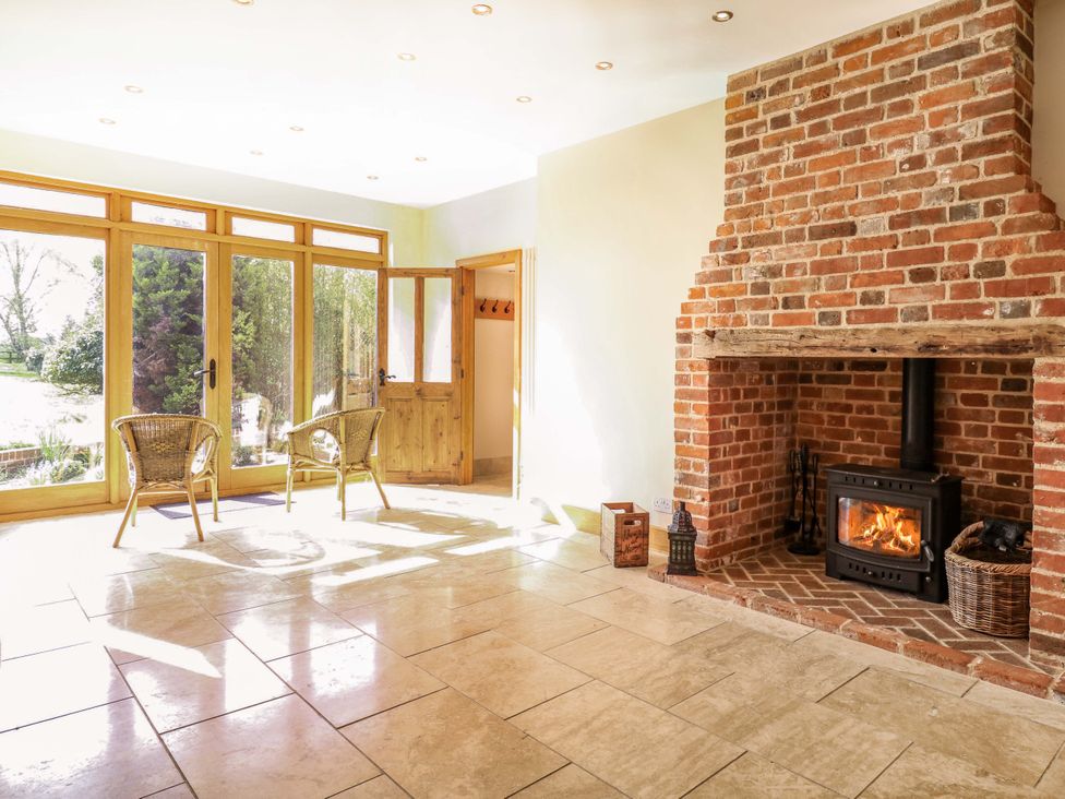 A living room with a fireplace and wicker chairs at Six Apples in Wethersfield near Finchingfield